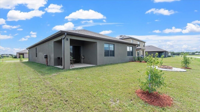 rear view of property featuring a fire pit, a yard, and a patio