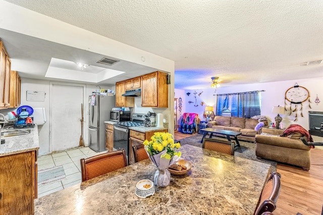 kitchen with sink, stainless steel appliances, a textured ceiling, and light tile patterned flooring