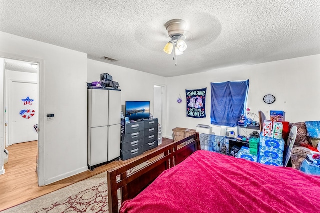 bedroom featuring wood-type flooring, a textured ceiling, and ceiling fan