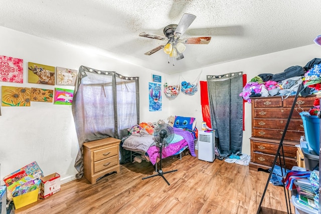 bedroom with ceiling fan, hardwood / wood-style floors, and a textured ceiling