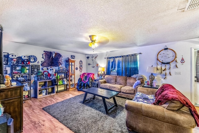 living room with ceiling fan, wood-type flooring, and a textured ceiling