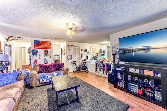 living room with ceiling fan, hardwood / wood-style floors, and a textured ceiling