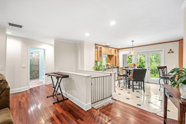 kitchen with pendant lighting, crown molding, wood-type flooring, and light brown cabinets