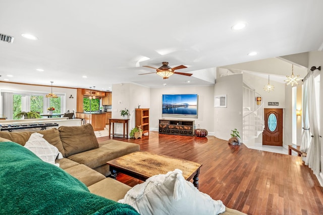 living room featuring ceiling fan with notable chandelier and wood-type flooring