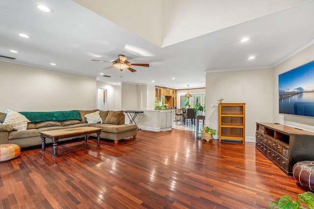 living room featuring dark wood-type flooring, ornamental molding, and ceiling fan