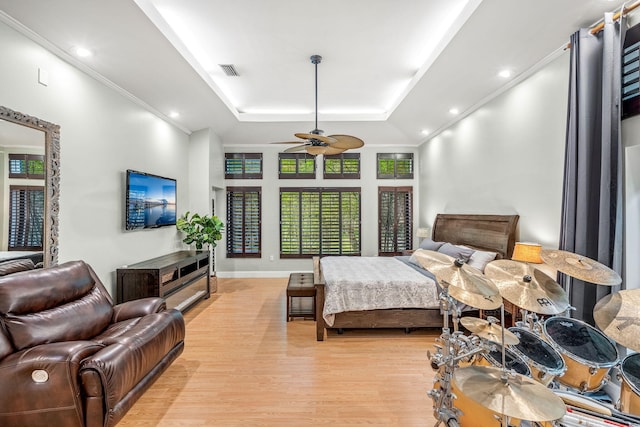 bedroom with light hardwood / wood-style flooring, ornamental molding, and a raised ceiling