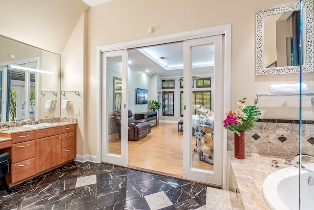 bathroom featuring vanity, a bath, and french doors