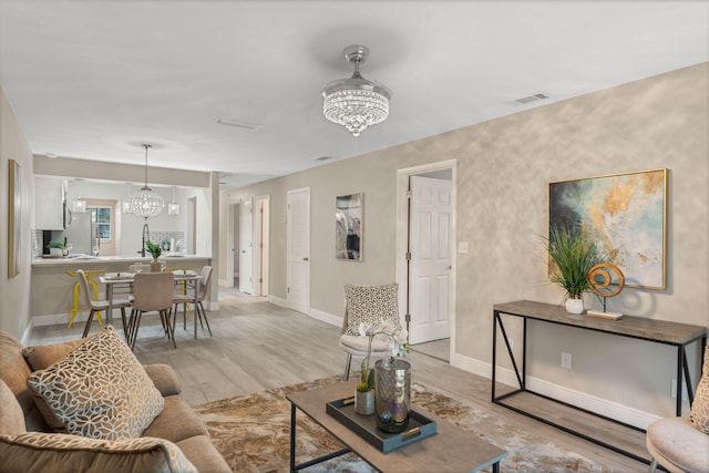 living room featuring a chandelier and light wood-type flooring