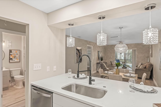 kitchen featuring decorative light fixtures, dishwasher, sink, white cabinets, and light hardwood / wood-style flooring