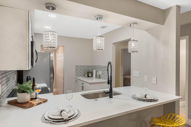 kitchen with sink, white cabinetry, decorative light fixtures, kitchen peninsula, and a notable chandelier