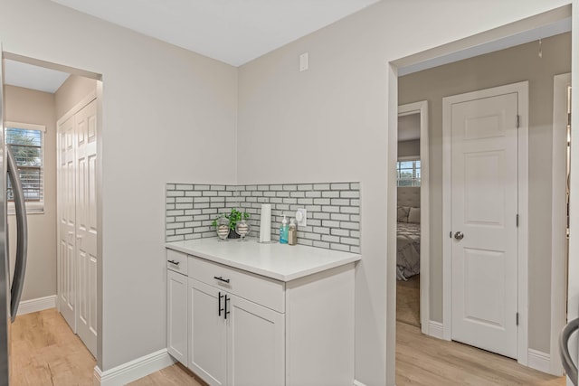 kitchen with white cabinetry, decorative backsplash, plenty of natural light, and light hardwood / wood-style floors