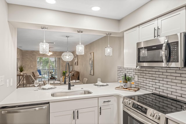 kitchen featuring appliances with stainless steel finishes, sink, white cabinets, and decorative light fixtures