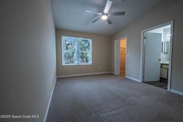 7667 N Wickham Rd Unit 1515, Melbourne, FL 32940 - unfurnished bedroom with carpet flooring, vaulted ceiling, a walk in closet, baseboards, and ensuite bath