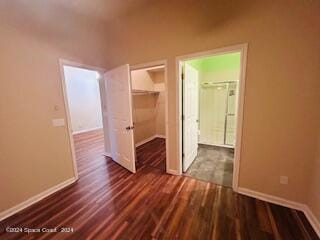 unfurnished bedroom featuring a spacious closet, a closet, and dark hardwood / wood-style floors