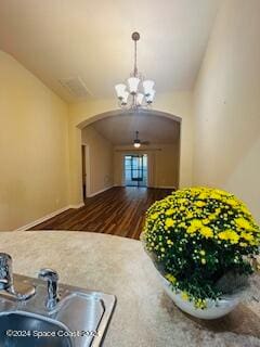 kitchen featuring vaulted ceiling, an inviting chandelier, dark wood-type flooring, and sink