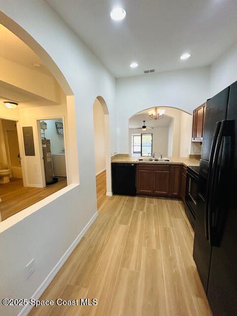 kitchen with black appliances, light countertops, light wood-style floors, and a sink