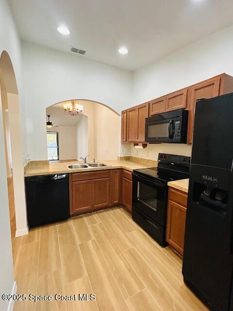 kitchen with visible vents, light countertops, arched walkways, black appliances, and a sink