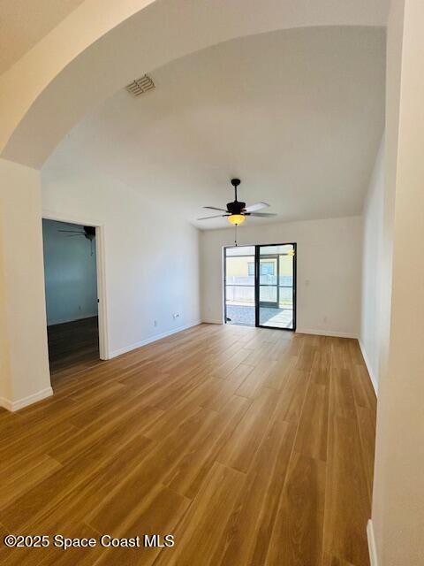 spare room with visible vents, light wood-style flooring, arched walkways, baseboards, and ceiling fan