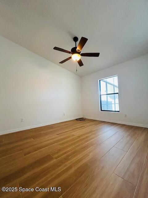 spare room featuring a ceiling fan, wood finished floors, and baseboards