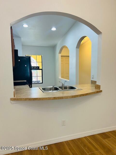 kitchen with a sink, baseboards, wood finished floors, and freestanding refrigerator