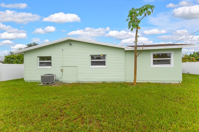 back of property with central AC and a yard