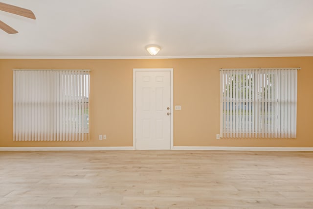 empty room featuring crown molding, light wood-type flooring, and ceiling fan