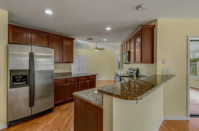 kitchen with a breakfast bar area, kitchen peninsula, ceiling fan, stainless steel appliances, and light hardwood / wood-style floors