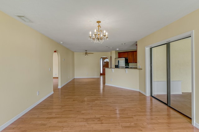 unfurnished living room with light wood-type flooring and ceiling fan with notable chandelier