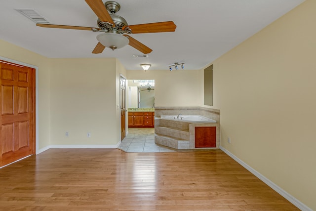 unfurnished living room featuring light tile patterned flooring, rail lighting, and ceiling fan