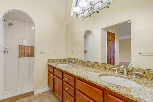 bathroom featuring tile patterned floors, tiled shower, and dual bowl vanity