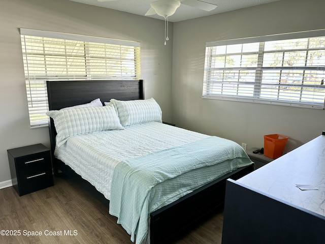 bedroom featuring ceiling fan, dark hardwood / wood-style floors, and multiple windows