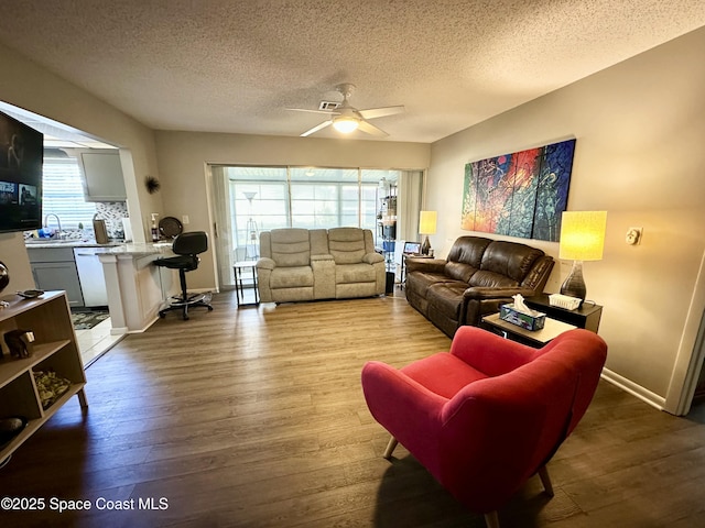 living room featuring ceiling fan, wood-type flooring, and a textured ceiling