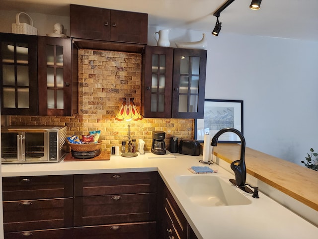 bar featuring tasteful backsplash, dark brown cabinetry, and sink