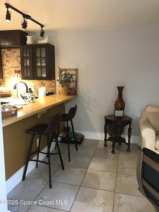 bar featuring tasteful backsplash and dark brown cabinets