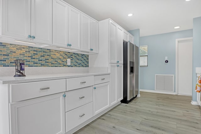 kitchen featuring tasteful backsplash, white cabinetry, light hardwood / wood-style flooring, and stainless steel fridge with ice dispenser