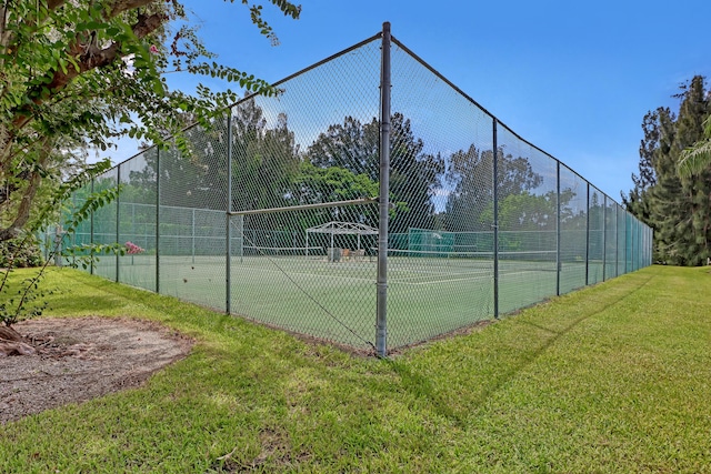 view of tennis court featuring a lawn