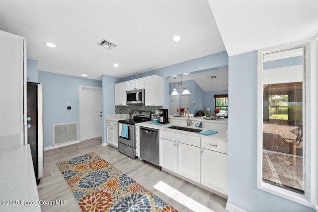 6209 S Mirror Lake Dr Unit 7, Sebastian, FL 32958 - kitchen with stainless steel appliances, a sink, light countertops, white cabinets, and light wood-style flooring