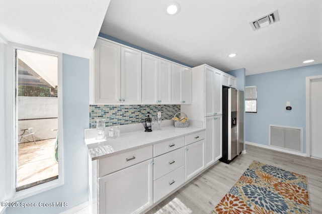 6209 S Mirror Lake Dr Unit 7, Sebastian, FL 32958 - kitchen featuring stainless steel fridge with ice dispenser, white cabinets, light wood finished floors, decorative backsplash, and recessed lighting