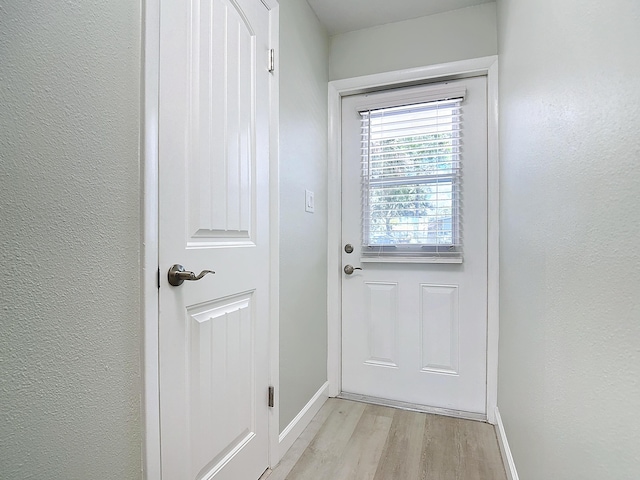 entryway with a textured wall, light wood-type flooring, and baseboards