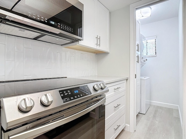 kitchen featuring washer and dryer, white cabinets, light countertops, appliances with stainless steel finishes, and tasteful backsplash