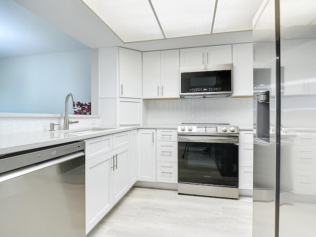 kitchen with stainless steel appliances, light countertops, and white cabinets