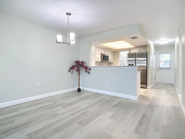 interior space with baseboards, a notable chandelier, visible vents, and light wood finished floors