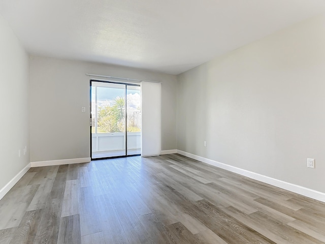 spare room featuring light wood-type flooring and baseboards