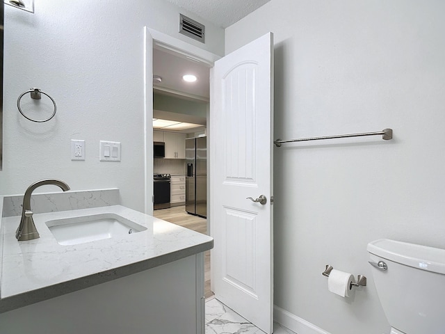 bathroom featuring visible vents, toilet, marble finish floor, a textured ceiling, and vanity