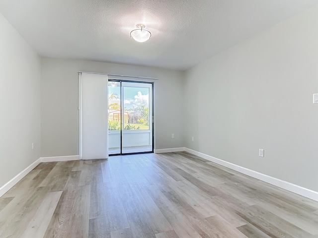 unfurnished room featuring light wood-style floors, a textured ceiling, and baseboards