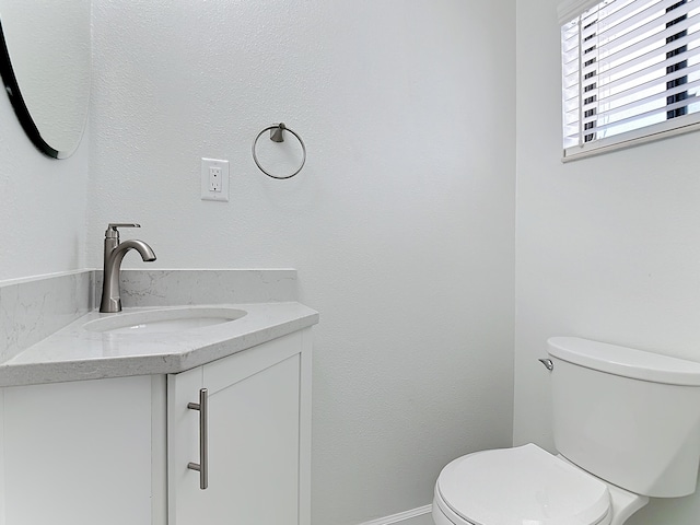 bathroom featuring toilet, baseboards, and vanity