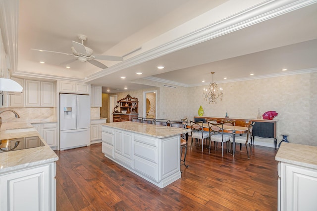 kitchen with wallpapered walls, crown molding, white refrigerator with ice dispenser, and a center island