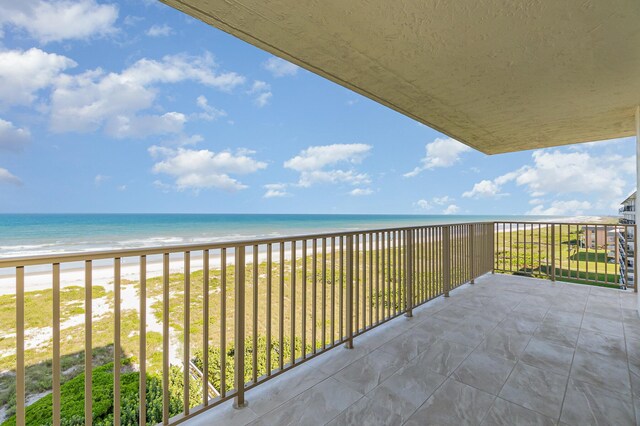 balcony featuring a view of the beach and a water view