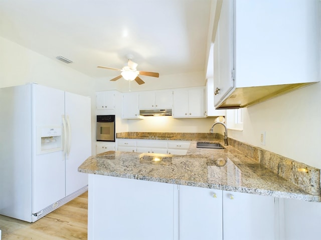 kitchen featuring sink, white refrigerator with ice dispenser, kitchen peninsula, oven, and white cabinets