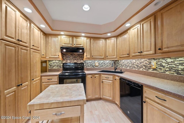 kitchen with tasteful backsplash, under cabinet range hood, black appliances, a raised ceiling, and a sink